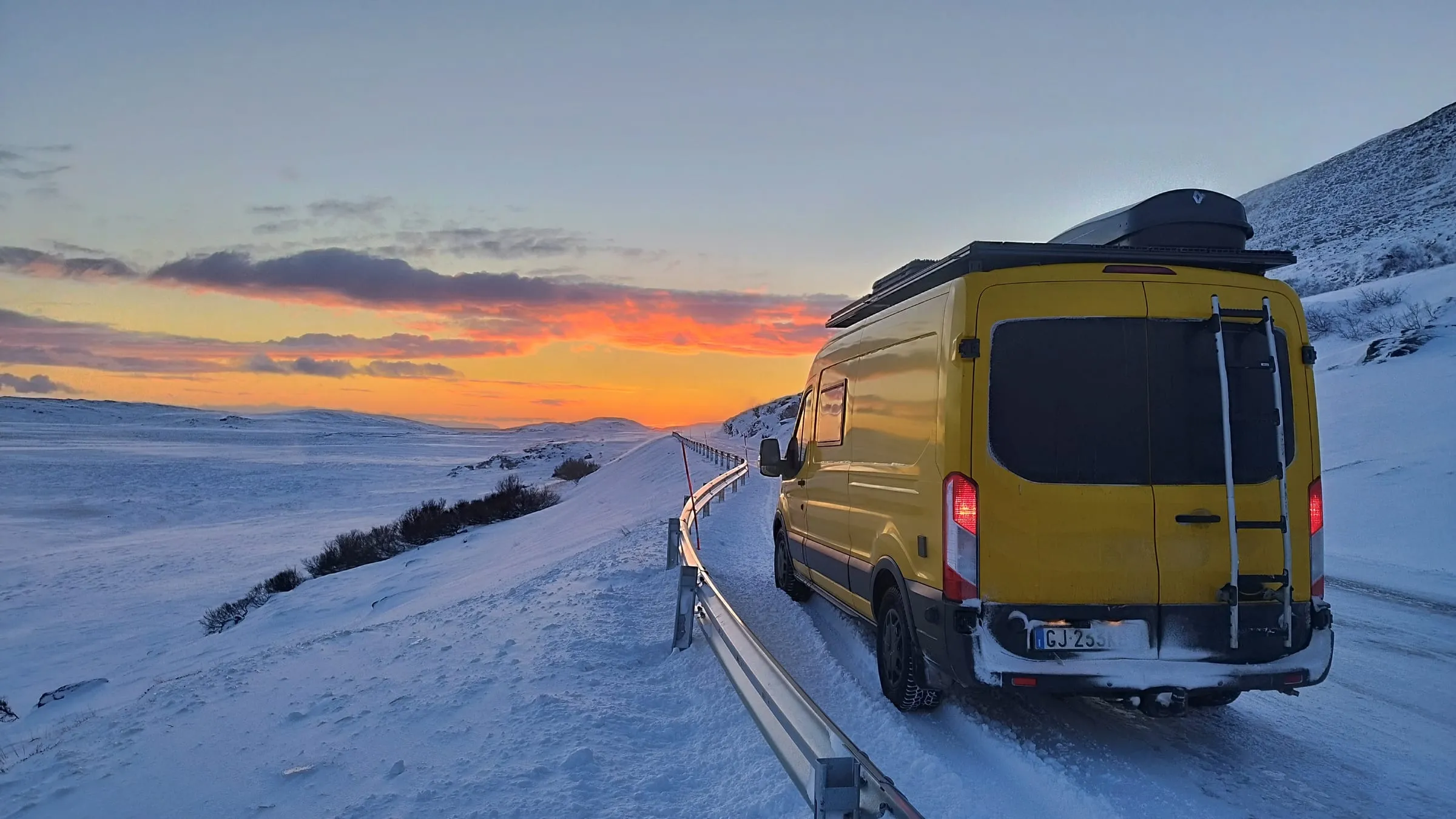 Unser gelber Ford Transit auf einer verschneiten Straße im Norden Norwegens bei Sonnenuntergang